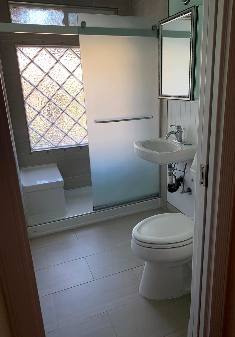 Small bathroom with a frosted sliding shower door, pedestal sink and light gray floor tile
