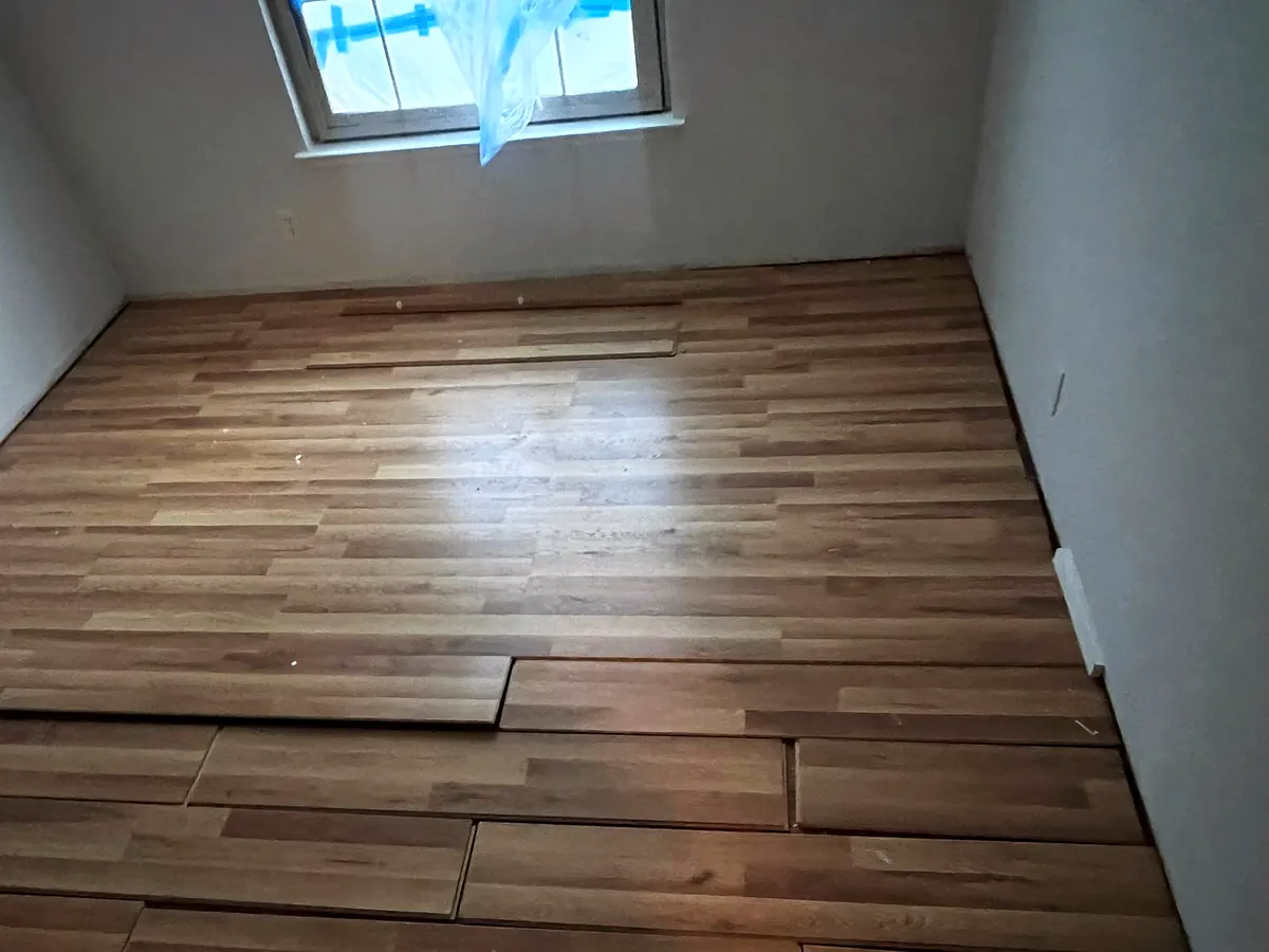 Plank flooring halfway installed in an empty room under a skylight