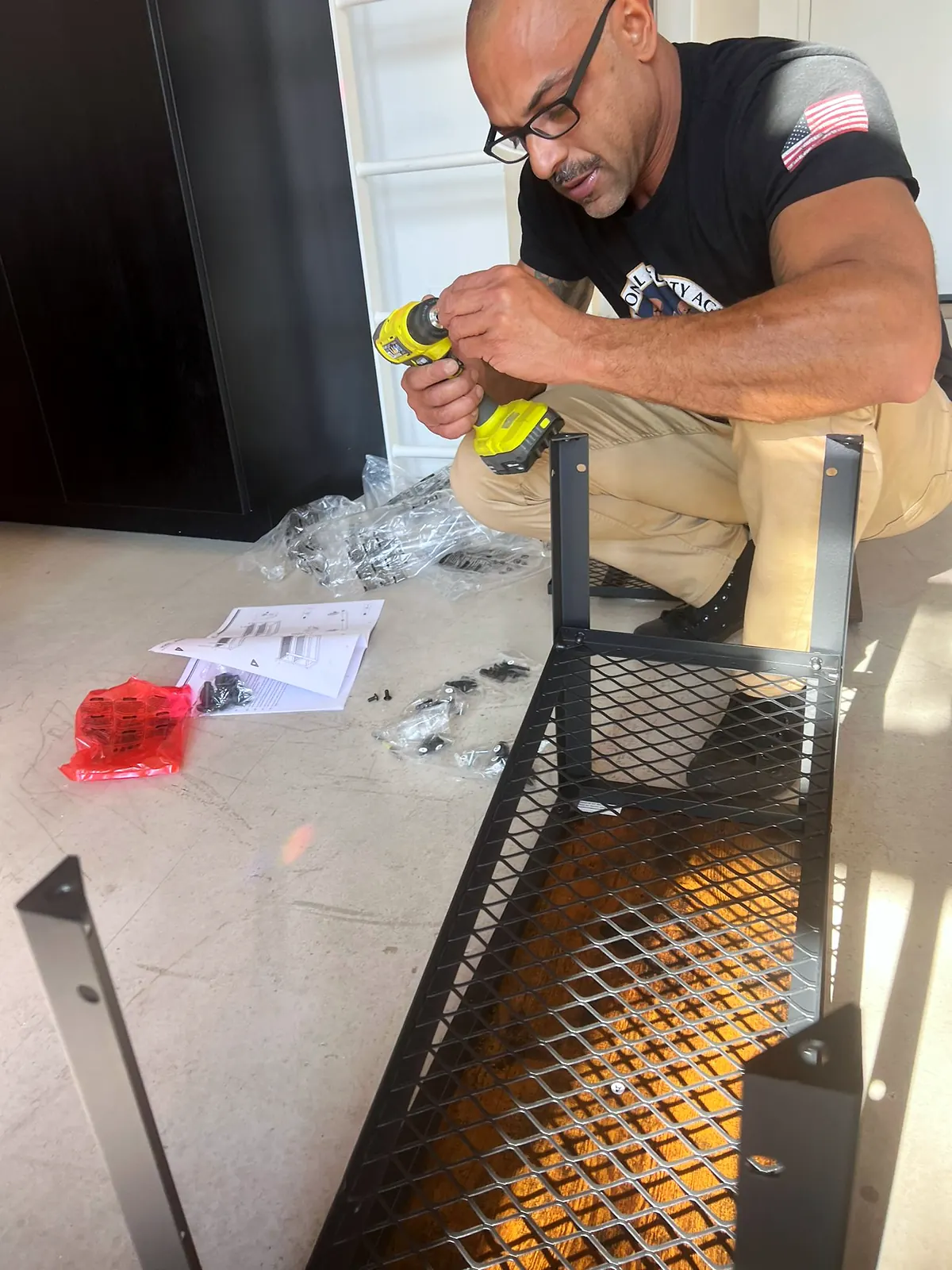 Junior driving a screw into a black metal shelf frame with a cordless drill